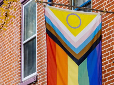 Pride flag hanging in small town neighborhood with windows and f